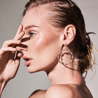 Unique statement gold hoop earrings showcasing a modern silhouette and a touch of artisanal crochet artistry.